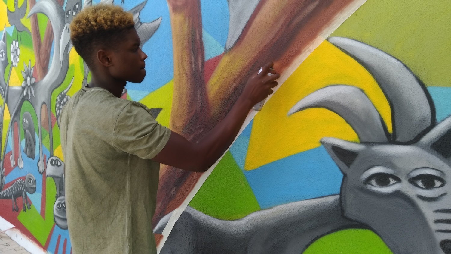 fotografia de jovem a pintar um mural de arte urbana no bairro do vale da amoreira